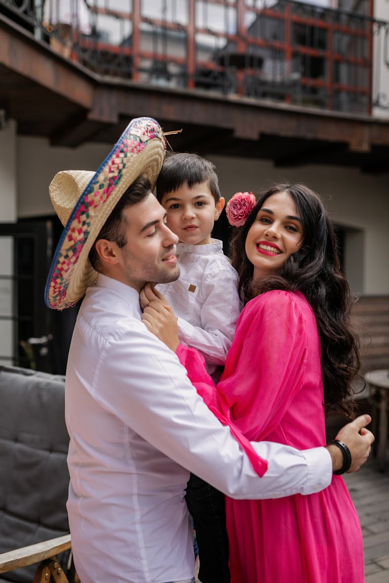 Smiling Hispanic family embracing with a child in a sombrero, celebrating together.